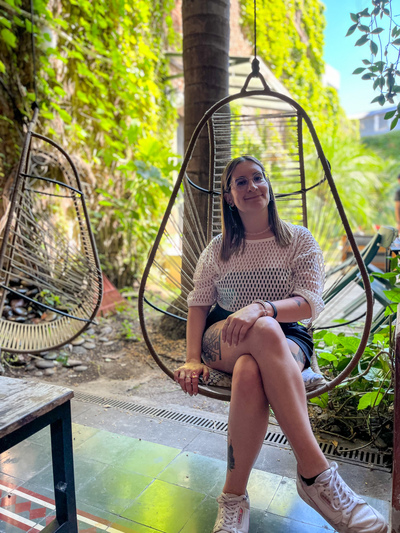 Una mujer en una silla colgante en un jardín.